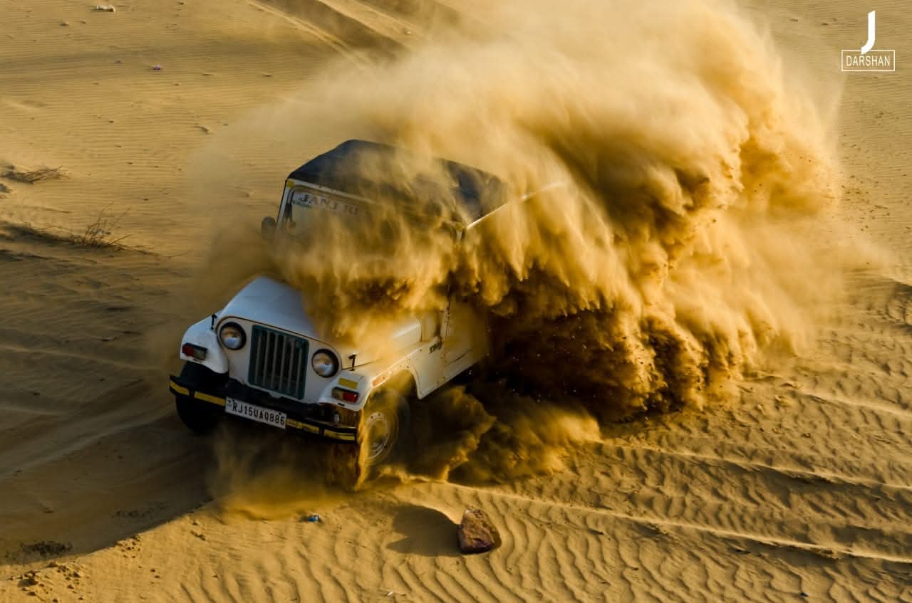 Jeep safari driving over golden desert dunes